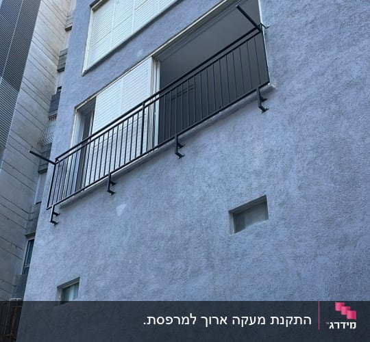 התקנת מעקה ברזל שחור עם סורגים ישרים בחלון בניין מגורים